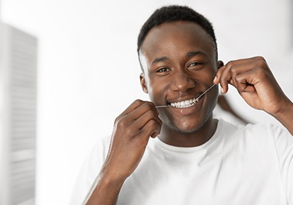 Man smiling while flossing his teeth