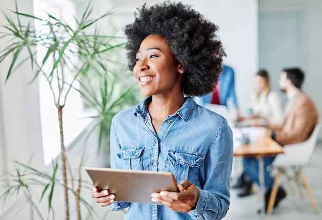 Woman smiling while holding tablet in office