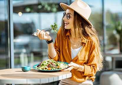 Smiling woman eating salad outside