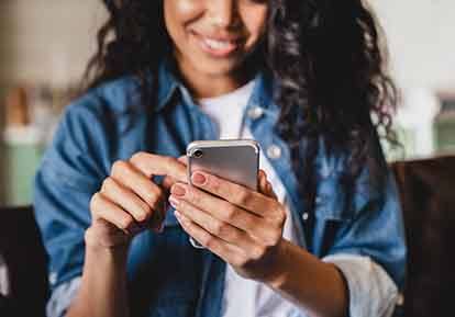 Smiling woman dialing number on cell phone